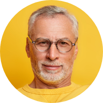 serious-self-confident-mature-man-raises-arm-shows-biceps-being-strong-powerful-holds-paper-cup-coffee-wears-casual-jumper-isolated-yellow-wall